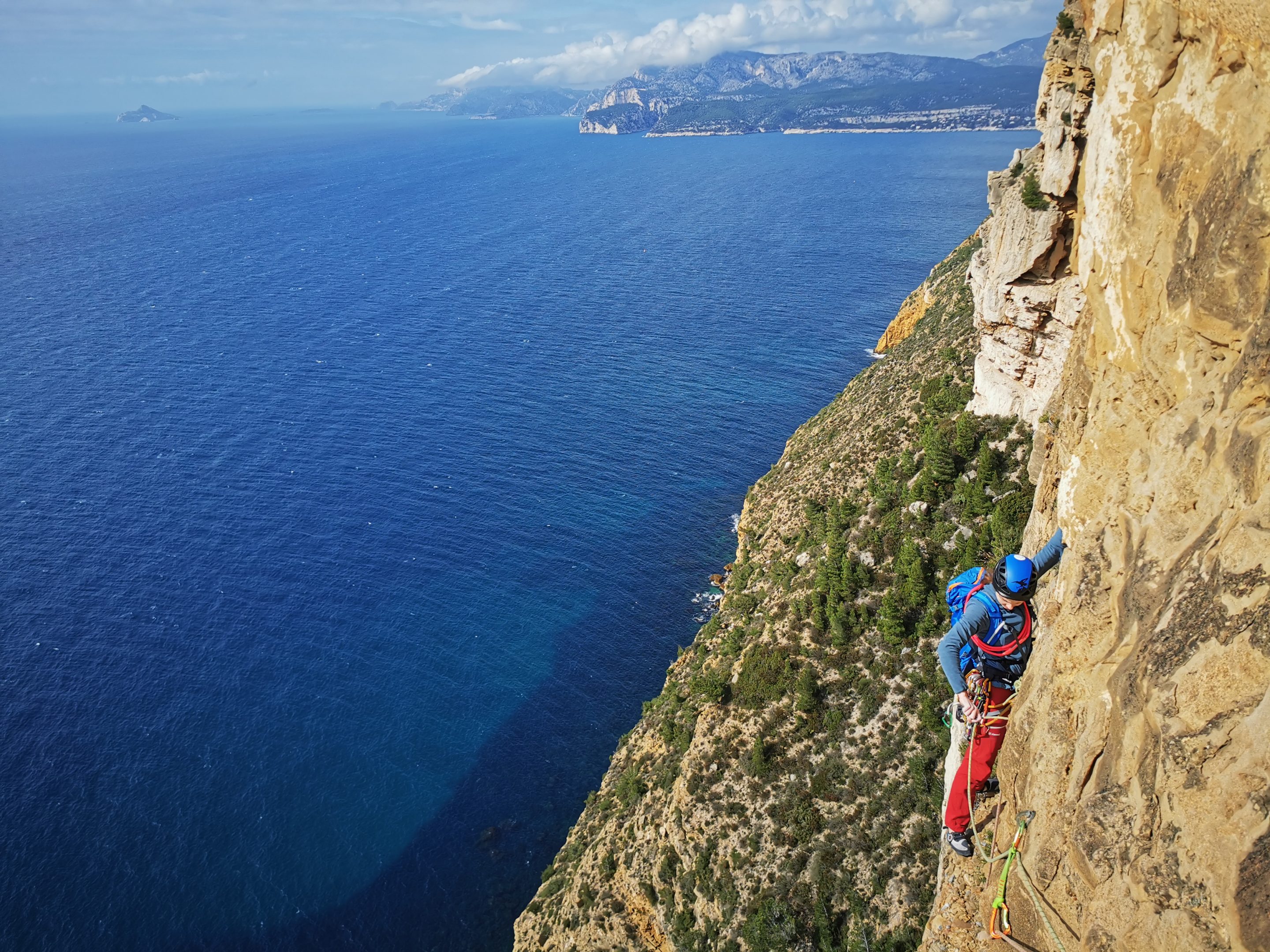 Une grimpeuse débutante escalade une grande voie dans les calanques de Marseille