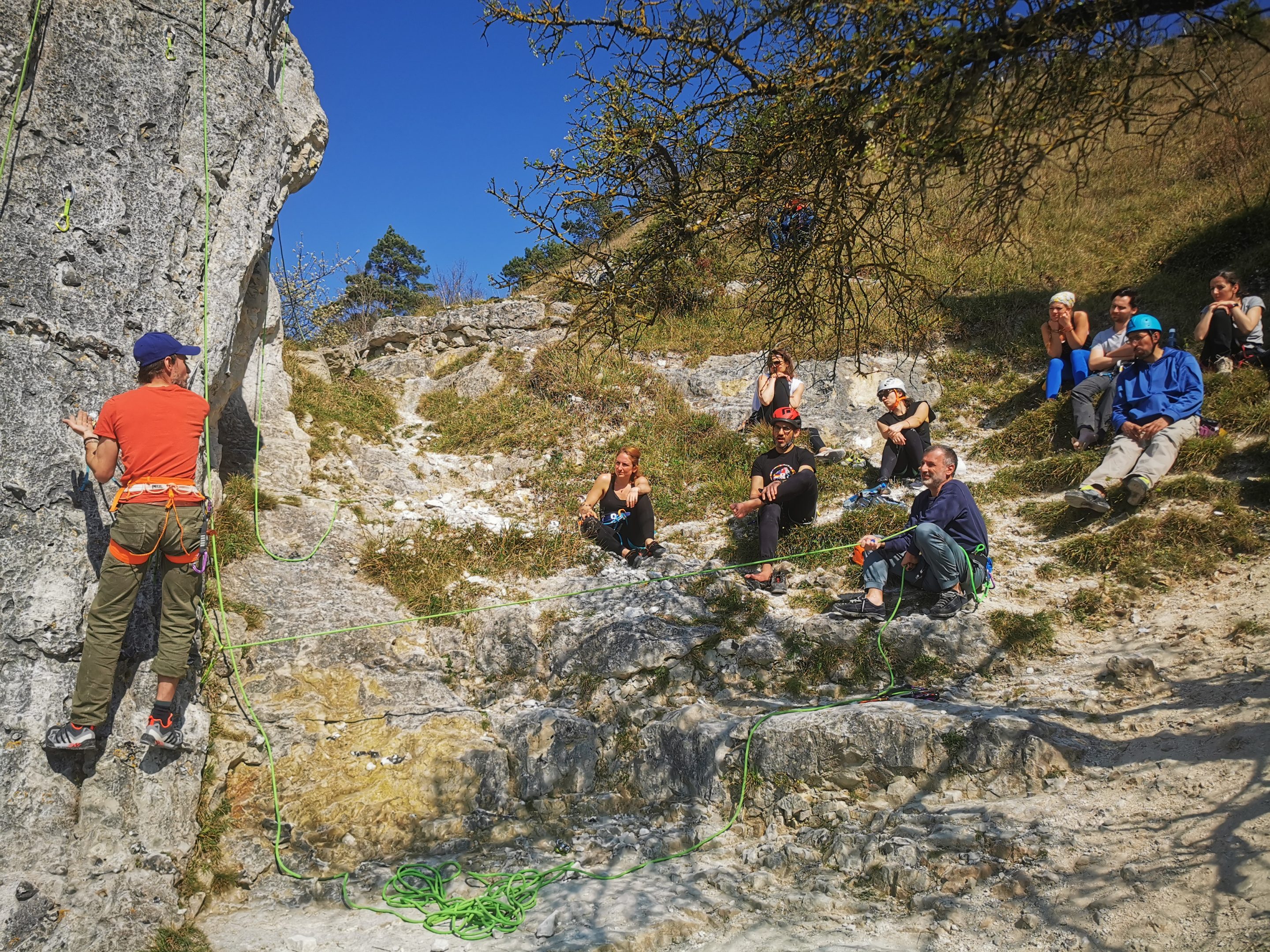 Un groupe avec son moniteur apprend à assurer en escalade de voie au pied de la falaise du Val Saint Martin